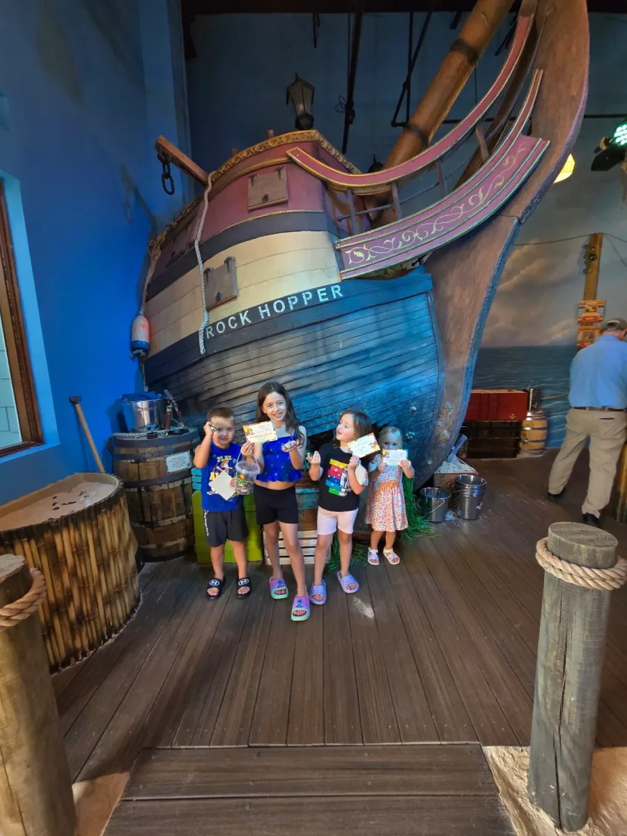 Four kids showing off their treasures in front of the Rock Hopper ship